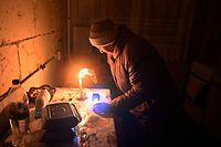Uma idosa acende uma vela no seu apartamento num edifício residencial, parcialmente destruído como resultado do bombardeamento da Rússia, na aldeia de Gorenka, região de Kiev, a 13 de dezembro de 2022.