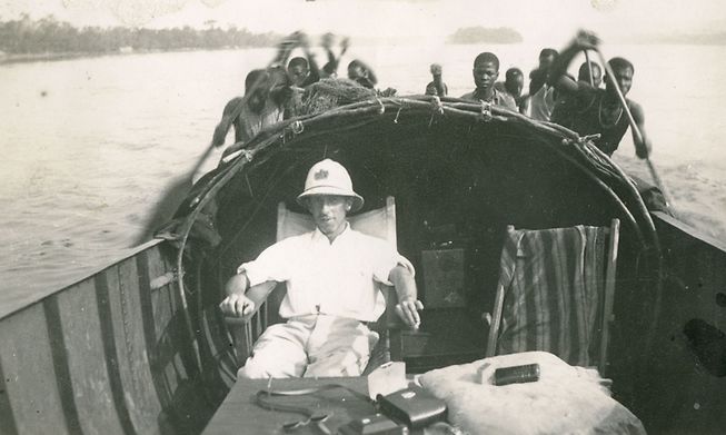 A Luxembourg colonial administrator on a boat powered by Congolese paddlers, 1930s