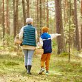 mushroom picking season, leisure and people concept - grandmother and grandson with baskets walking in forest