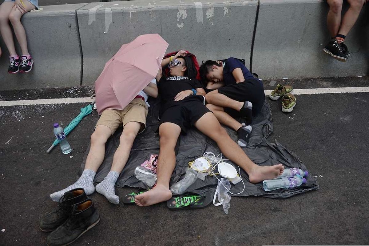 TOPSHOTS Pro-democracy demonstrators rest after overnight protests near the Hong Kong government headquarters on October 2, 2014. Hong Kong has been plunged into the worst political crisis since its 1997 handover as pro-democracy activists take over the streets following China's refusal to grant citizens full universal suffrage. AFP PHOTO / DALE DE LA REY