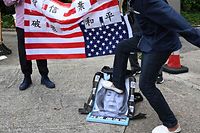 Um protestante pró-Pequim pontapeia um cartaz com o retrato de Nancy Pelosi, num protesto em frente ao consulado americano em Hong Kong.