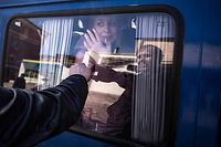 TOPSHOT - A woman waves to say good bye to her husband as she leaves on a bus, a day after a rocket attack at a train station in Kramatorsk, on April 9, 2022. - At least 52 people were killed, including five children, following a rocket attack on April 8 on a train station in the eastern Ukrainian city of Kramatorsk that is being used for civilian evacuations, according to Donetsk region governor. (Photo by FADEL SENNA / AFP)