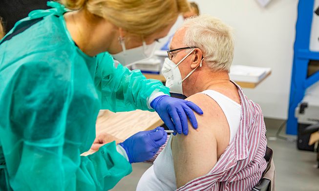 A healthcare worker giving a Covid-19 vaccine to an elderly man