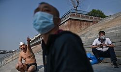 A man wears a face mask as people gather along the Yangtze river in Wuhan, China's central Hubei province on April 16, 2020. - China has largely brought the coronavirus under control within its borders since the outbreak first emerged in the city of Wuhan late last year. (Photo by Hector RETAMAL / AFP)