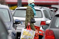 13.03.2020, Österreich, Salzburg: Eine Frau mit Mundschutz trägt ihre Einkäufe über den Parkplatz eines Einkaufszentrums. Im Kampf gegen das Coronavirus müssen in Österreich ab kommender Woche viele Geschäfte vorübergehend schließen. Lebensmittelmärkte und Apotheken dürfen weiterhin offen bleiben, sagte Bundeskanzler Kurz am Freitag in Wien. Foto: Barbara Gindl/APA/dpa +++ dpa-Bildfunk +++