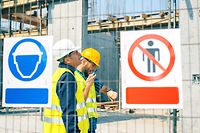 Engineer and construction site manager dealing with blueprints and projects. Construction site warning signs. Arbeitsunfall, Arbeitsunfälle, sicherheit am Arbeitsplatz, Baustelle, Helmpflicht