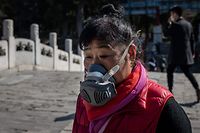 A woman wearing a facemask as a preventive measure against the COVID-19 coronavirus walks on a bridge at the Summer Palace in Beijing on March 17, 2020. - China reported on March 17 just one new domestic coronavirus infection but found 20 more cases imported from abroad, with more regions imposing quarantines on foreign arrivals in a bid to stem the disease being brought in from overseas. (Photo by NICOLAS ASFOURI / AFP)