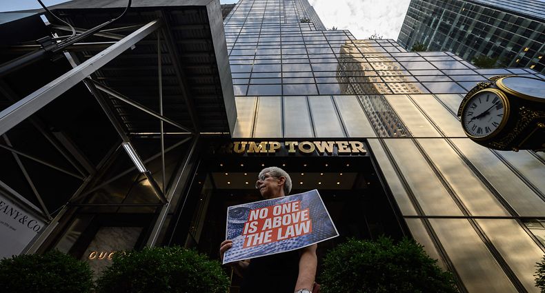 A demonstrator holds a sign reading "No One is Aove the Law" outside of the Trump Tower building in New York City on August 9, 2022. - Former US president Donald Trump said on August 8, 2022, that his Mar-A-Lago residence in Florida was being "raided" by FBI agents in what he called an act of "prosecutorial misconduct." (Photo by Ed JONES / AFP)