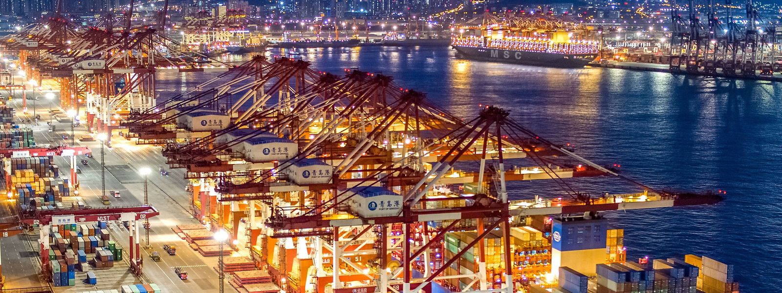 Containerschiffe liegen im nächtlich beleuchteten Containerterminal des Hafens von Qingdao: im Juli steigerte China seine Exporte um 18 Prozent gegenüber dem Vormonat, während die Importe lediglich um 2,3 Prozent stiegen.