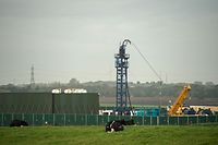 (FILES) In this file photo taken on October 16, 2018 Cows graze in a field as work gets under way at the Preston New Road drill site where energy firm Cuadrilla Resources have commenced fracking (hydraulic fracturing) operations to extract shale gas, near the village of Little Plumpton, near Blackpool, north west England on October 16, 2018. - The British government called a temporary halt on November 2 to the controversial process of "fracking" due to fears it could trigger earthquakes. (Photo by OLI SCARFF / AFP)