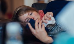 Ill woman using mobile phone at home.