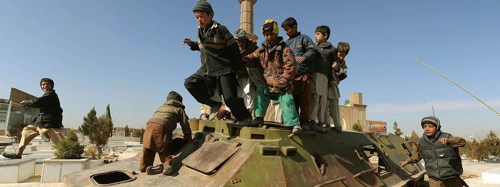 Afghanische Kinder spielen auf Kriegsgerät aus der Sowjetära.