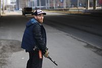 Homem voluntário com uma arma protege uma estrada em Kiev, capital. 