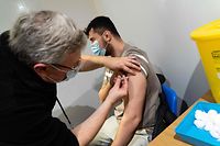 A member of the public receives a dose of a Covid-19 vaccine inside a vaccination centre set up at Grim's Dyke Golf Club in north west London on December 26, 2021. - England pressed ahead with its Covid-19 immunisation campaign on Sunday in the race to inoculate as many people possible while the number of cases of the Omicron coronavirus variant soars. (Photo by Niklas HALLE'N / AFP)