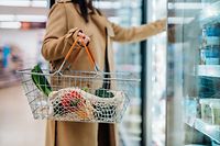 Close up shot of woman carrying shopping basket and shopping groceries in supermarket. City solo life concept. Single person.