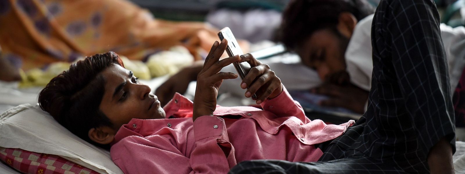 Ein indischer Wanderarbeiter beschäftigt sich während des nationalen Lockdowns mit seinem Smartphone.