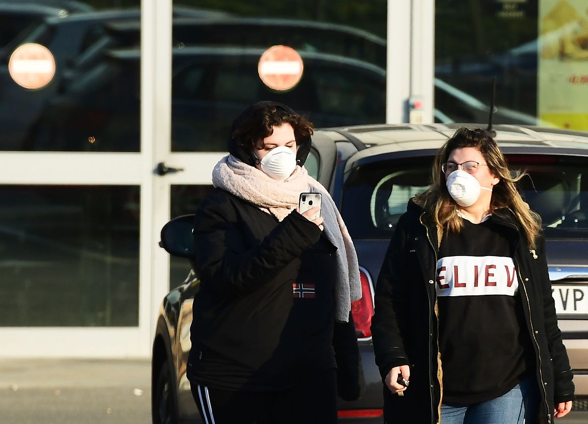 Passanten mit Atemschutzmasken stehen in Codogno vor den geschlossenen Türen eines Supermarkts. 