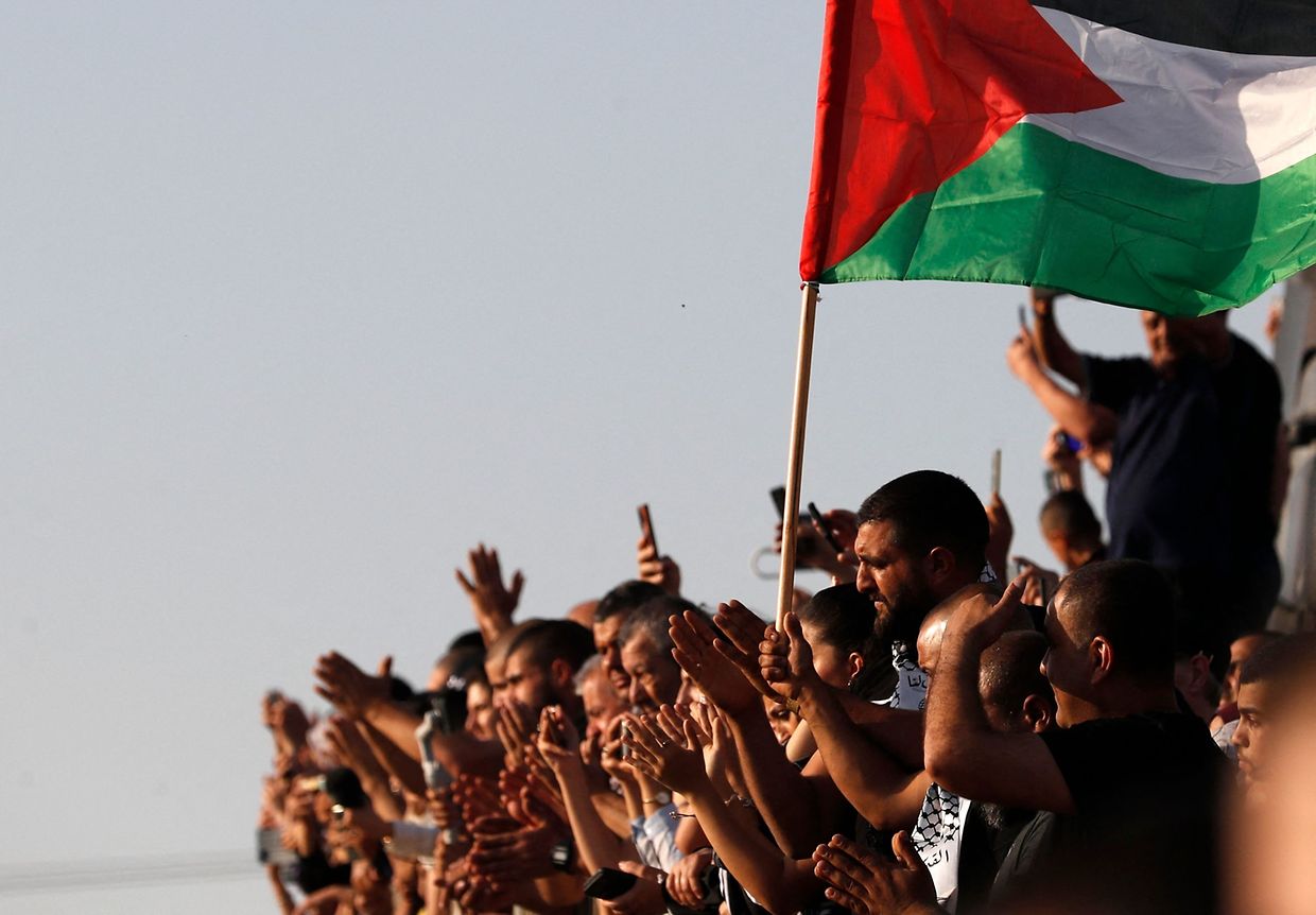 Os enlutados levantam uma bandeira palestiniana durante o funeral de Mohammad Kiwan, um palestiniano de 17 anos que sucumbiu às suas feridas depois de ter sido baleado pelas tropas israelitas durante os protestos contra a ocupação israelita. (Photo by Ahmad GHARABLI / AFP)
