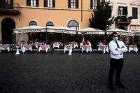 A waiter wearing a face mask awaits the early closure of bars and restaurants in Piazza Navona in Rome on October 26, 2020, as the country faces a second wave of infections to the Covid-19, caused by the novel coronavirus. - Italy's Prime Minister Giuseppe Conte tightened nationwide coronavirus restrictions on October 25, 2020 after the country registered a record number of new cases, despite opposition from regional heads and street protests over curfews. Cinemas, theatres, gyms and swimming pools must all close under the new rules, which come into force on October 26, 2020 and run until November 24, while restaurants and bars will stop serving at 6pm, the prime minister's office said. (Photo by Tiziana FABI / AFP)