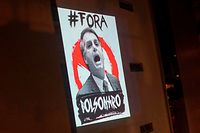 TOPSHOT - View of a projection depicting Brazil's President Jair Bolsonaro which reads "Bolsonaro Out" as part of daily protests called "Panelacos", during the outbreak of the novel coronavirus COVID-19 in Rio de Janeiro, Brazil, on March 26, 2020. (Photo by Mauro PIMENTEL / AFP)