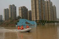 Rescue workers ride on a rubber boat following heavy rain that flooded and claimed the lives of at least 33 people earlier in the week, in the city of Zhengzhou, in China's Henan province on July 23, 2021. (Photo by Noel Celis / AFP)