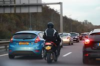 Un motocycliste remontant une file de voiture: la pratique reste strictement interdite au Luxembourg