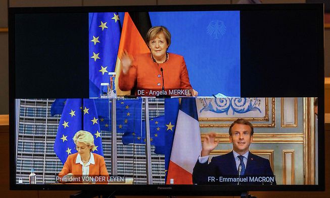 German Chancellor Angela Merkel (top), French President Emmanuel Macron and European Commission President Ursula von der Leyen are seen on a screen during a videoconference on Wednesday before the start of this week's EU summit in Brussels