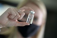 A woman holds a pharmaceutical vial of German glass company Schott at the company's headquarters in Mainz, western Germany, on November 20, 2020. - As expectations grow that the first Covid-19 jabs will be administered in a matter of weeks, German glassmaker Schott is quietly doing what it has been for months: churning out vials that will hold the vaccine. (Photo by Daniel ROLAND / AFP)