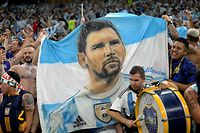 (ARQUIVOS) Nesta foto de arquivo tirada em 26 de novembro de 2022, os torcedores da Argentina tocam bateria enquanto seguram uma bandeira do país com um desenho do atacante # 10 da Argentina, Lionel Messi, antes da partida de futebol do Grupo C da Copa do Mundo de 2022 do Catar entre Argentina e México no Lusail Stadium em Lusail, ao norte de Doha.  - "Muchachos", a música que se tornou um hino popular para Lionel Messi e para a seleção campeã do mundo, nasceu como uma versão de um canto de arquibancada e rapidamente se tornou um fenômeno que identifica os torcedores e a conquista da terceira estrela alviceleste.  (Foto de JUAN MABROMATA/AFP)