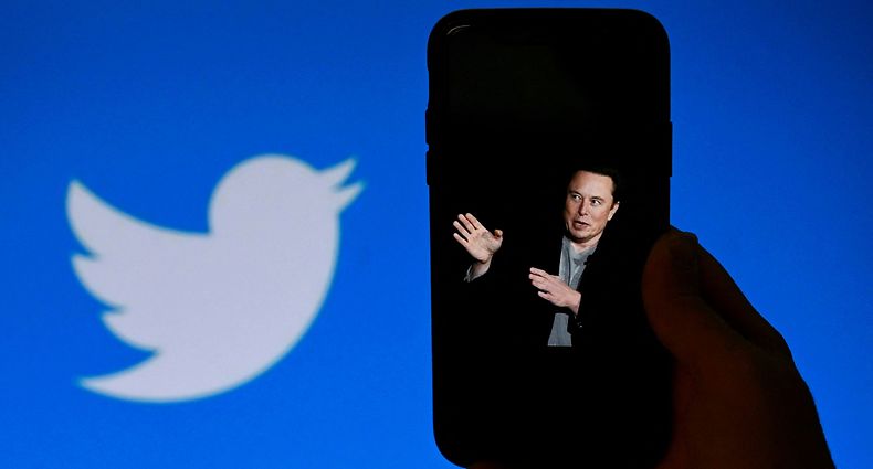 (FILES) In this file photo taken on October 4, 2022, a phone screen displays a photo of Elon Musk with the Twitter logo shown in the background, in Washington, DC. - A landslide of Twitter users responding to an informal poll by new owner Elon Musk voted in favor of a general amnesty for suspended accounts on the platform. The "yes/no" informal poll comes as Musk faces pushback that his criteria for content moderation is subject to his personal whim, with reinstatements decided for certain accounts and not others. Of 3.16 million respondents to Musk's tweeted poll question, 72.4 percent said Twitter should allow suspended accounts back on Twitter as long as they have not broken laws or engaged in "egregious spam," Musk posted. (Photo by OLIVIER DOULIERY / AFP)