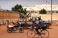 TOPSHOT - A man rides a bicycle past a soldier sitting on a pick-up truck as Burkina Faso soldiers are seen deployed in Ouagadougou on September 30, 2022. - Shots were heard early Friday around Burkina Faso's presidential palace and the headquarters of its military junta, which seized power in a coup last January, witnesses told AFP.
Several main roads in the capital Ouagadougou were blocked by troops and state television was cut, broadcasting a blank screen saying: "no video signal". (Photo by Olympia DE MAISMONT / AFP)
