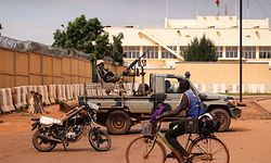 TOPSHOT - A man rides a bicycle past a soldier sitting on a pick-up truck as Burkina Faso soldiers are seen deployed in Ouagadougou on September 30, 2022. - Shots were heard early Friday around Burkina Faso's presidential palace and the headquarters of its military junta, which seized power in a coup last January, witnesses told AFP. Several main roads in the capital Ouagadougou were blocked by troops and state television was cut, broadcasting a blank screen saying: "no video signal". (Photo by Olympia DE MAISMONT / AFP)