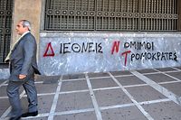 A man walks past a 'Bank of Greece' as a graffiti reads on the wall 'IMF, 'International Legal Terrorists"  in Athens on April 23, 2010.Greece appealed for a debt rescue from the EU and IMF on Friday and said that help should arrive within days, in a dramatic turn for the eurozone at risk from Greek contagion.  Prime Minister George Papandreou told his nation in a televised speech that the aid was a "national need" which would "offer us a safe port to allow our boat to float again."<br />AFP PHOTO / LOUISA GOULIAMAKI