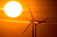 ARCHIV - 11.03.2022, Niedersachsen, Laatzen: Die Sonne geht hinter Windrädern in der Region Hannover auf. (zu dpa: "Studie: Energiewende-Tempo reicht nicht für 1,5-Grad-Ziel") Foto: Julian Stratenschulte/dpa +++ dpa-Bildfunk +++