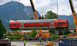 Einer der insgesamt drei umstürzten Waggons der verunglückten Regionalbahn hängt bei der Bergung an einem Spezialkran. Zwei Tage nach dem Zugunglück von Garmisch-Partenkirchen gehen die Aufräumarbeiten voran.