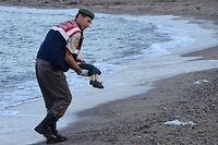 (FILES) This file photo taken on September 2, 2015 shows a Turkish police officer carrying a migrant child's dead body (Aylan Shenu) off the shores in Bodrum, southern Turkey, after a boat carrying refugees sank while reaching the Greek island of Kos.
A year ago, the tragic death of a three-year-old Syrian boy shocked Europe as an unprecedented crisis saw hundreds of thousands of migrants and refugees arrive on the continent. The photo of three-year-old Aylan Kurdi's tiny body washed up on a Turkish beach goes viral on September 2, 2015, as Europe faces its worst migrant crisis since World War II. Aylan is one of some 3,700 people who die trying to reach Europe in 2015, including his mother and his brother, according to the International Organization for Migration (IOM)
 / AFP PHOTO / DOGAN NEWS AGENCY / Nilufer Demir