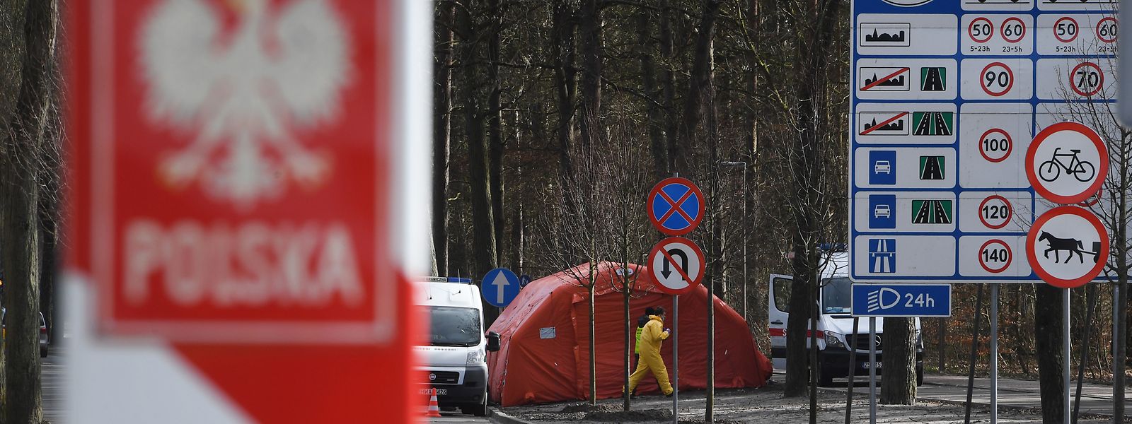 Ein Mitarbeiter des polnischen Rettungsdienstes kontrolliert in Schutzkleidung in Swinoujscie (Swinemünde) in Polen an der polnisch-deutschen Grenze Reisebusse.