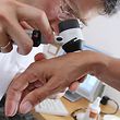 ARCHIV - 25.06.2008, Bayern, Buchloe: ILLUSTRATION - Ein Hautarzt untersucht in seiner Praxis mit einem Vergrößerungsglas die Haut einer Patientin bei einer Hautkrebs-Früherkennung. (zu dpa «Binnen zehn Jahren 67 300 Sachsen-Anhalter mit Krebsdiagnose») Foto: Karl-Josef Hildenbrand/dpa +++ dpa-Bildfunk +++