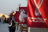 People walk past a banner of the Qatar 2022 mascot La'eeb at a beach in Doha on November 10, 2022, ahead of the Qatar 2022 FIFA World Cup football tournament. (Photo by GABRIEL BOUYS / AFP)