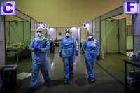 TOPSHOT - Healthcare workers wearing protective gear prepare to attend  patients at the Portimao Arena sports pavilion converted in a field hospital for Covid-19 patients at Portimao, in the Algarve region, on February 9, 2021. (Photo by PATRICIA DE MELO MOREIRA / AFP)