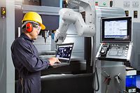 Maintenance engineer using laptop computer control automatic robotic hand with CNC machine in smart factory, Industry 4.0 concept - Image