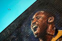 A helicopter flies over a Kobe Bryant mural in downtown Los Angeles on January 26, 2020. - Nine people were killed in the helicopter crash which claimed the life of NBA star Kobe Bryant and his 13 year old daughter, Los Angeles officials confirmed on Sunday. Los Angeles County Sheriff Alex Villanueva said eight passengers and the pilot of the aircraft died in the accident. The helicopter crashed in foggy weather in the Los Angeles suburb of Calabasas. Authorities said firefighters received a call shortly at 9:47 am about the crash, which caused a brush fire on a hillside. (Photo by Apu GOMES / AFP)