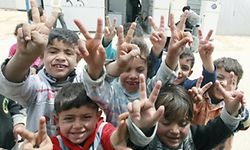Syrian refugee children make the V-sign for victory as they pose for the camera in the Zaatari refugee camp, a seven-square-kilometre (2.8-square-mile) camp that is home to more than 100,000 refugees, on April 15, 2014, some 10 days after riots killed one refugee and left dozens, mainly policemen, injured. The kingdom which neighbours Syria along its northern borders is hosting more than 500,000 Syrian refugees. AFP PHOTO/KHALIL MAZRAAWI