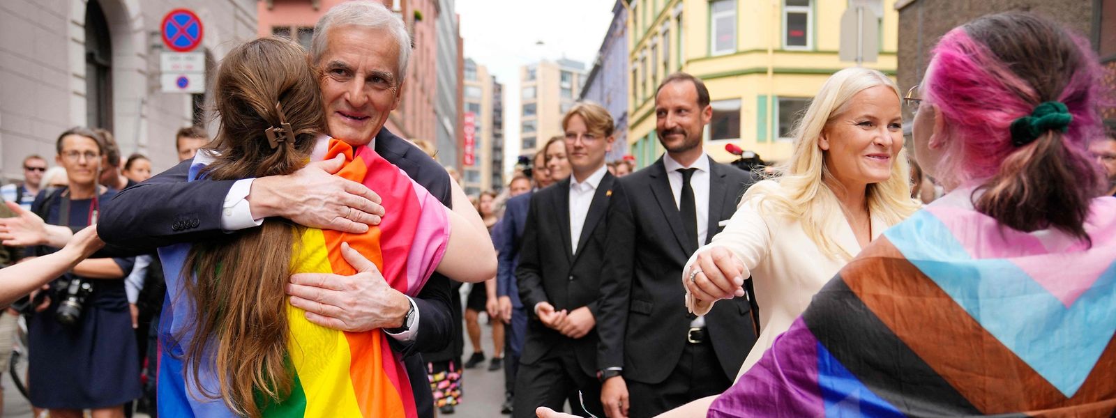 Le Premier ministre norvégien Jonas Gahr Store et la princesse héritière Mette-Marit de Norvège réconfortent des personnes avec un drapeau LGBT.