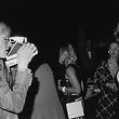 19th July 1973: American artist Andy Warhol (1928 - 1987) taking a photograph of British author and actor Tessa Dahl with his Polaroid camera during a Mother's Day party at the Four Seasons, New York City. (Photo by Tim Boxer/Hulton Archive/Getty Images)