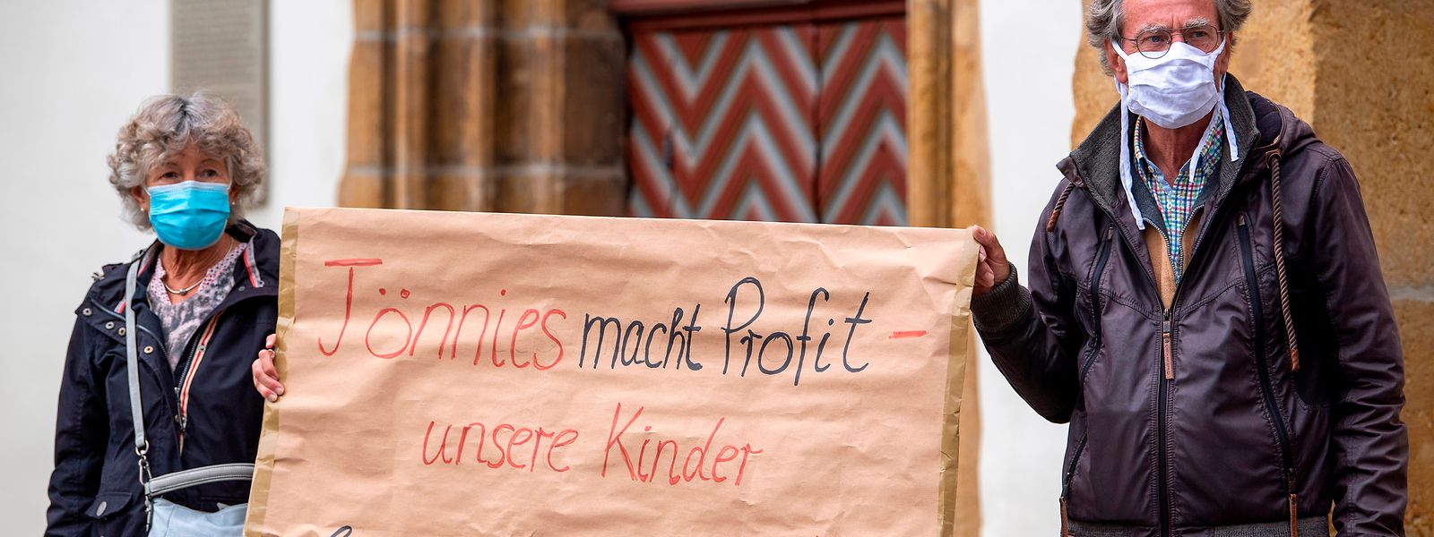 Demonstranten halten während einer Mahnwache zur Situation beim Fleischwerk Tönnies auf dem Marktplatz in Rheda-Wiedenbrück ein Schild mit der Aufschrift "Tönnies macht Profit - unsere Kinder bezahlen den Preis!"