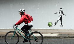 TOPSHOT - A cyclist passes a Coronavirus-inspired piece of graffiti in Glasgow on April 4, 2020, as life in Britain continues during the nationwide lockdown to combat the novel coronavirus pandemic. (Photo by ANDY BUCHANAN / AFP)