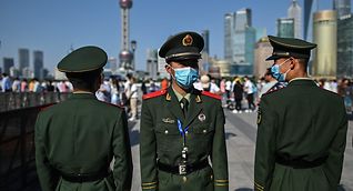 Chinese paramilitary policemen watch as people walk along the Shanghai waterfront on Saturday. The European Commission is expected to propose legislation this week that could limit EU market access to Chinese state-ownedcompanies.