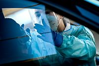 A medical staff attends a driver in his vehicle at the Covid-19 testing facility on the Spoor Oost site in Antwerp, on November 3, 2020. - Belgium is in a second lockdown as hospitalisations of COVID-19 patients reach record highs. (Photo by DIRK WAEM / Belga / AFP) / Belgium OUT