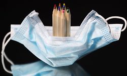 This picture shows an illustration of a protective face mask and coloring pencils taken in Paris on May 10, 2020, on the eve of the partial reopening of schools as France is scheduled on May 11 to start easing a lock down that began on March 17 aimed at curbing the spread of COVID-19, the novel corona virus. (Photo by JOEL SAGET / AFP)